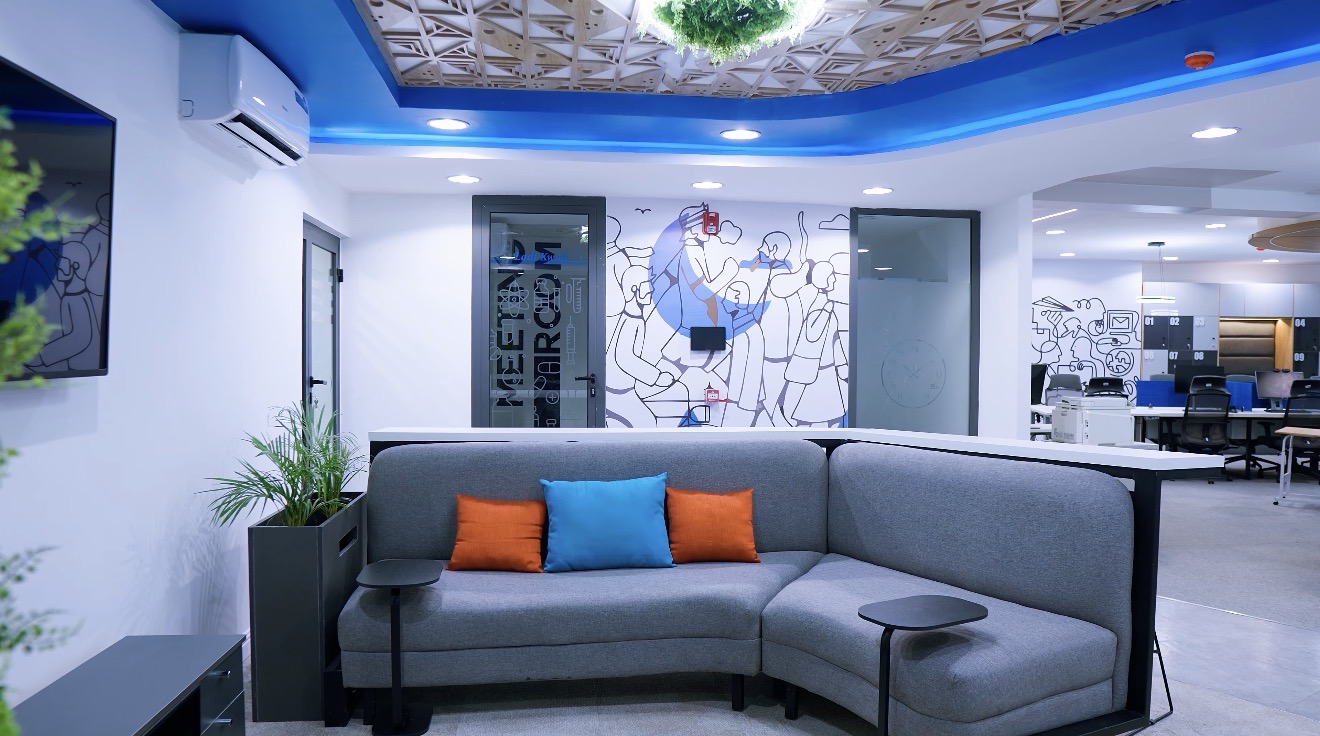 Roche Abuja collaboration lounge with curved seating, illustrated graphics and open workstations beyond.
