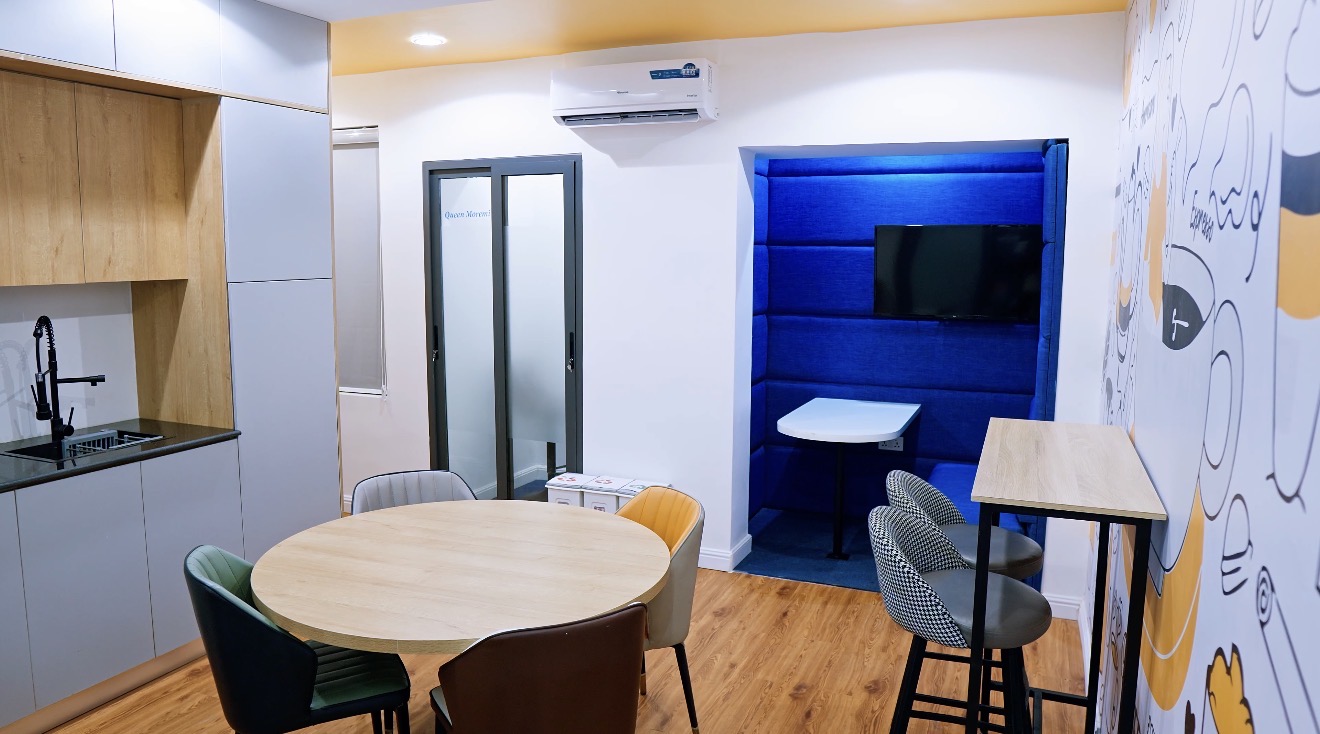 Roche Abuja breakout area with kitchenette, round table, varied seating, blue booth and illustrated feature wall.